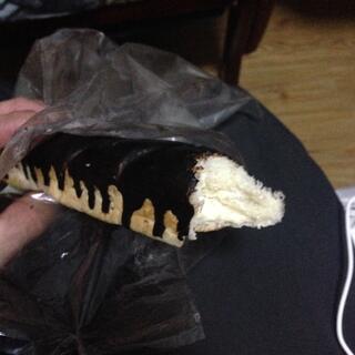 A fluffy bread roll filled with cream and coated in drizzled chocolate.