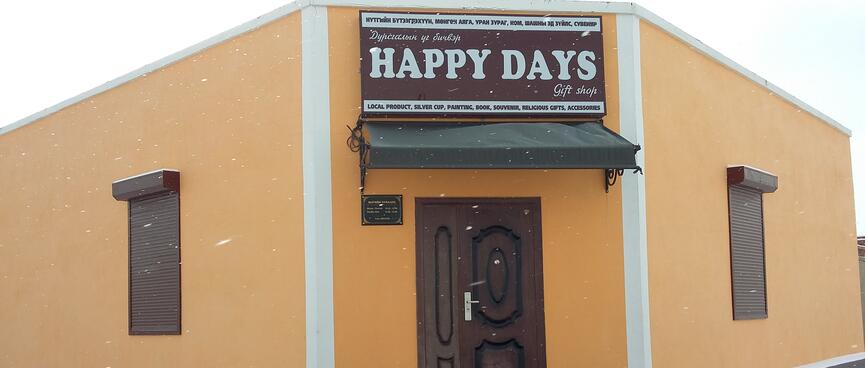 The Happy Days gift shop is an angular orange building with a large sign above the brown door.