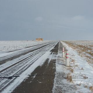 A snow-streaked highway, surrounded by snow.