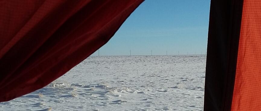 Blue sky and white snow as seen from the tent doorway.