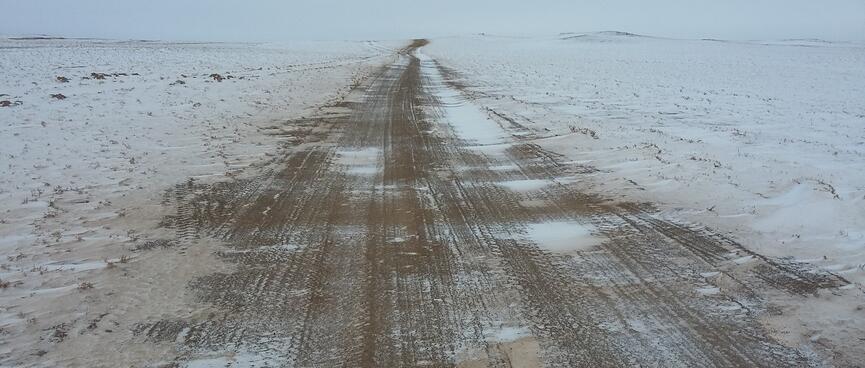 A brown 4WD track, partially shrouded in white snow.