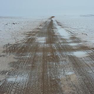 A brown 4WD track, partially shrouded in white snow.