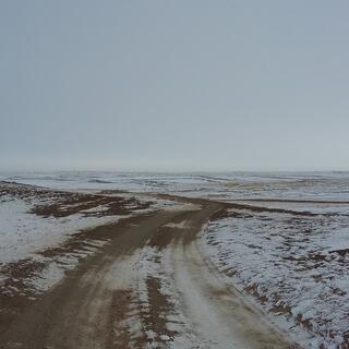 A junction of brown trails cutting through the white fields.