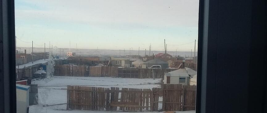 Simple cabins, traditional tent gers, rickity wooden fences and lamp posts in a snowy town.