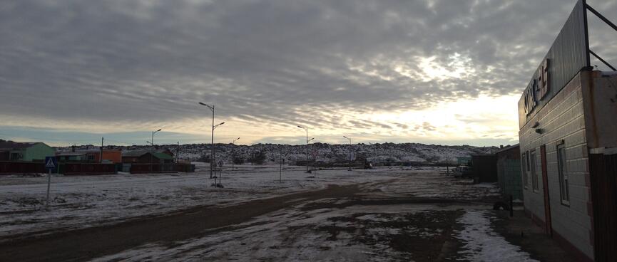 Grey mottled cloud over a yellow sky and snowy landscaoe.