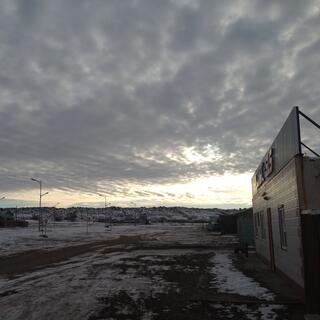 Grey mottled cloud over a yellow sky and snowy landscaoe.