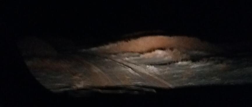 The vanʼs headlights illuminate a pile of dirt.