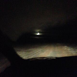 The vanʼs headlights illuminate the road, a bright light shines in the distance.