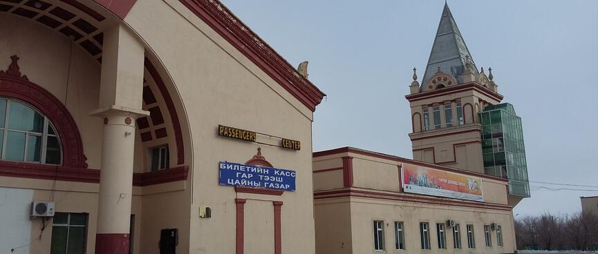 A building with a large entrance archway and a tower with a steep pointed roof.