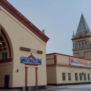 A building with a large entrance archway and a tower with a steep pointed roof.