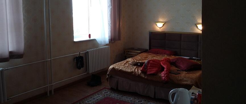 A double bed with a gold bedspread in a dimly lit hotel room.