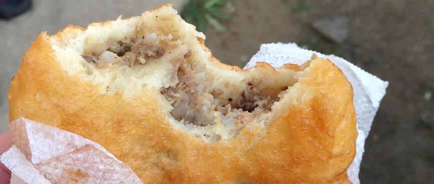 A disc-shaped crispy bread snack containing onion and meat.
