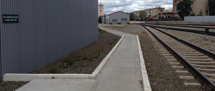 A clean and angular concrete path runs parallel to railway tracks, at Zabaikalsk station.