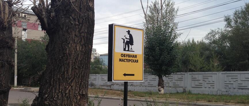 A roadside sign depicts a man hammering a new sole onto an upturned boot, in Chita.