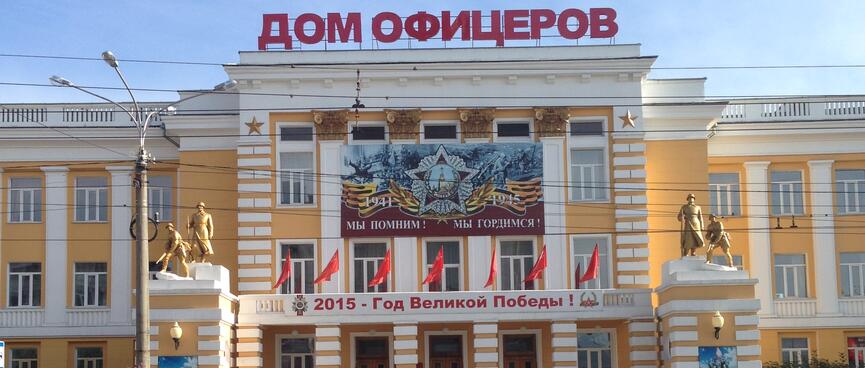 Bronze statues of soldiers stand guard outside a solid yellow building, in Chita.