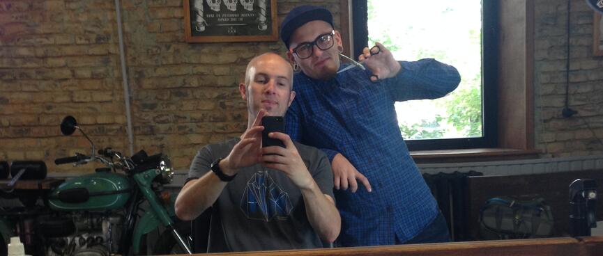 Germin leans on my chair while I take a photo of us in the mirror, at Bros hair salon in Chita.