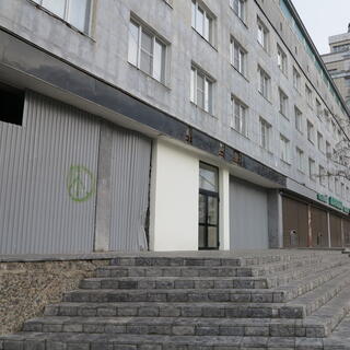 A peace symbol has been sprayed onto a corrugated iron fence patching a hole in an aging concrete monstrosity, in Chita.