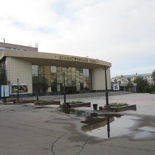 A squat building with a curved frontage, reflective windows and tiled walls, displays a few stage play posters, in Chita.