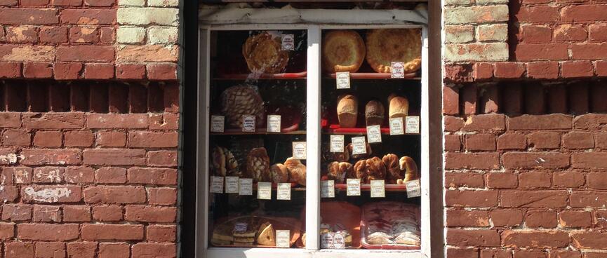 An arched window cut out in a brick wall hosts an elaborate display of baked goods, in Chita.