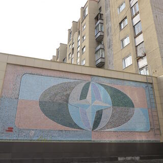 A mural is split into quadrants, and features a four point star on top of an oval globe, in Chita.