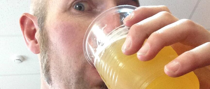 I drink the fish beer from a plastic cup.