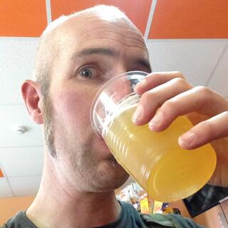 I drink the fish beer from a plastic cup.