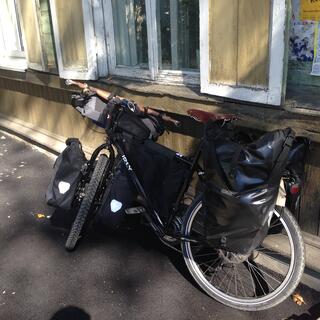 My bike leans against a wooden house with window shutters.