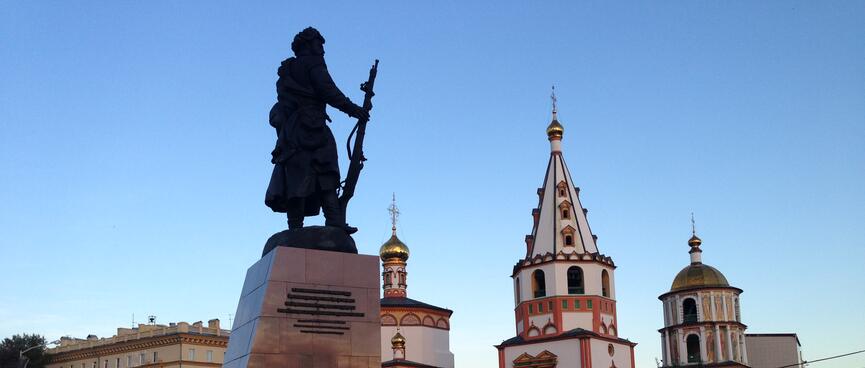 A statue of a Cossack soldier holding a rifle, and some ornate buildings.