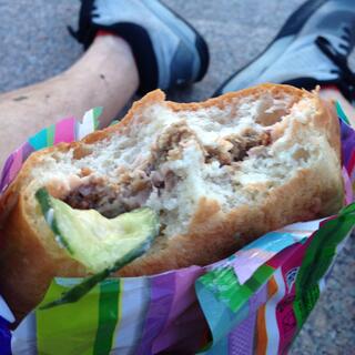 Thick bread buns, a layer of meat, and a floppy piece of cucumber.