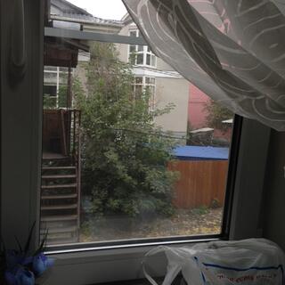 A net curtain is pulled back to reveal a paved courtyard and another set of wooden stairs.