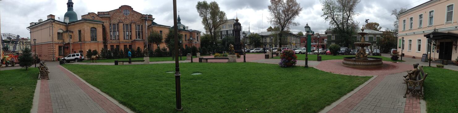 A paved path marks the boundary of a pedestrian square filled with enigmatic art, in Irkutsk.