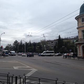 A large intersection is crossed by buses, vans, cars, tram lines and trolley bus wires.