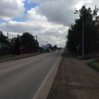 Trees and dirt footpaths border a long straight road.