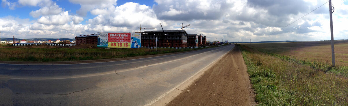 Half-finished townhouses are surrounded by empty fields and older bungalows.