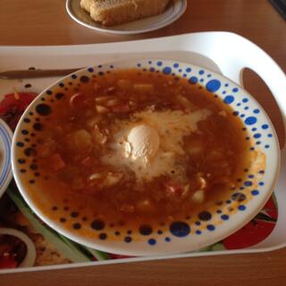Ham and vegetables in a red broth, with a dollop of sour cream, and a slice of bread.