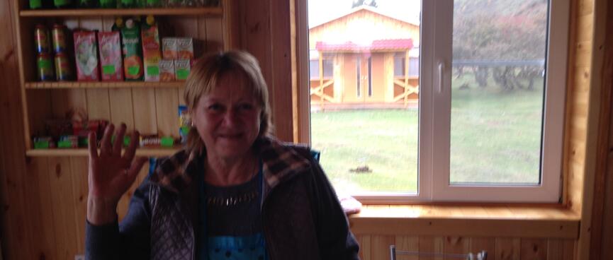 A Russian woman waves from behind the counter of her shop in Maloye Goloustnoye.