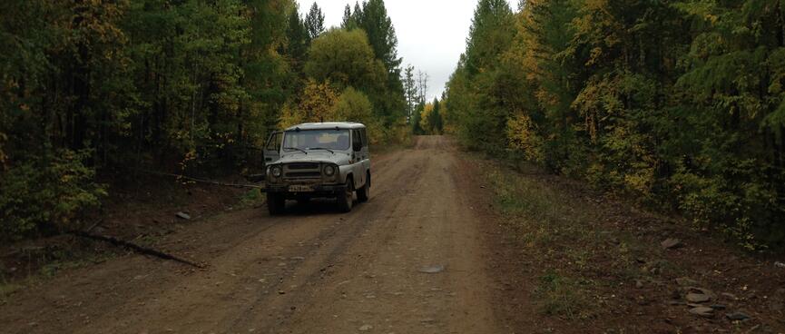 A battered grey jeep on the dirt road.