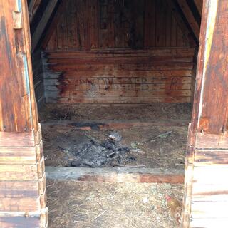 A pile of ashes, and black writing on wooden walls.