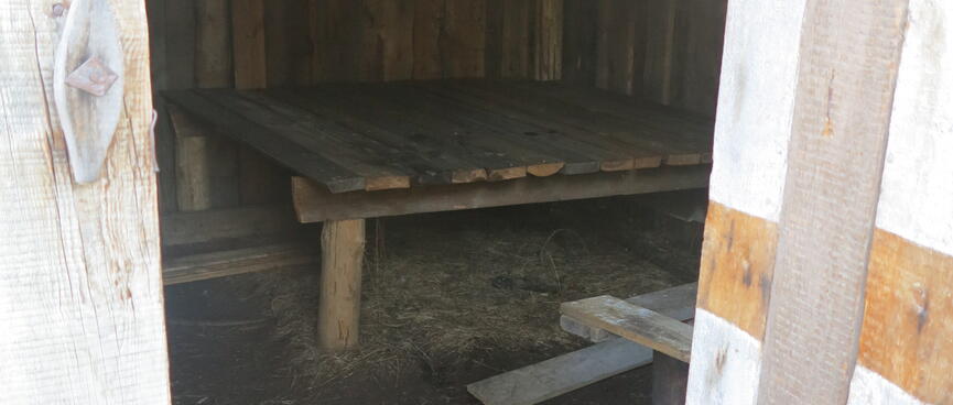 A small cabin contains a raised sleeping platform.