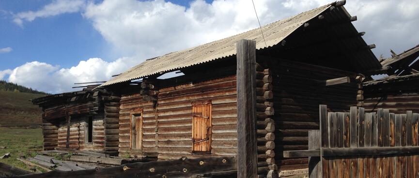 A log house with gaps in the roof where beams have fallen down.