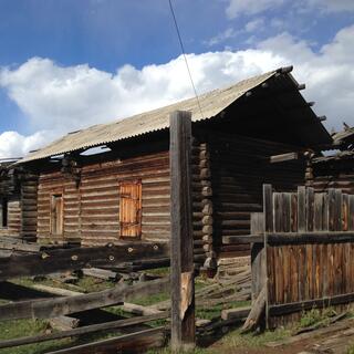 A log house with gaps in the roof where beams have fallen down.