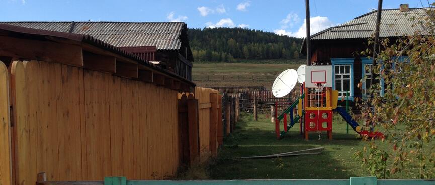 A plastic playground with slide and basketball hoop, and behind it two satellite dishes.