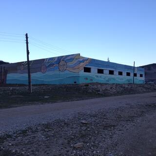 A shallow building with slit windows is painted in a mural.