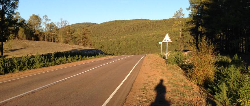 My long shadow extends towards a road sign.