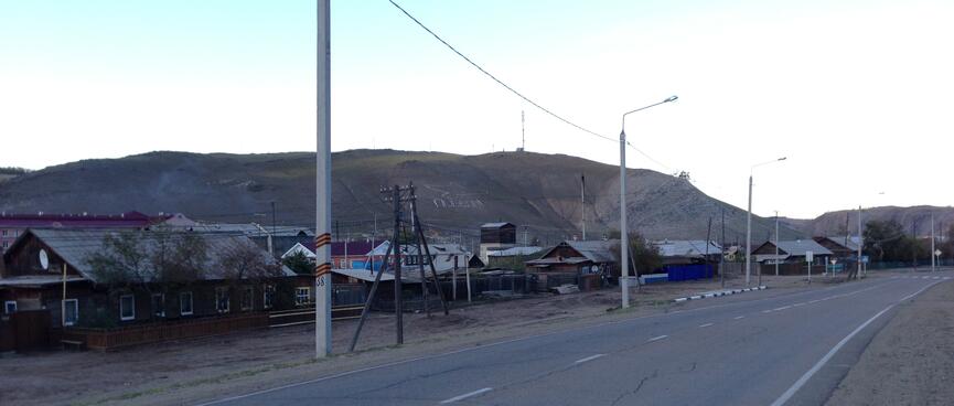 The outline of a bird is visible on the hill behind a roadside village.