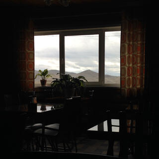 Mountains visible through the window of a dark room.