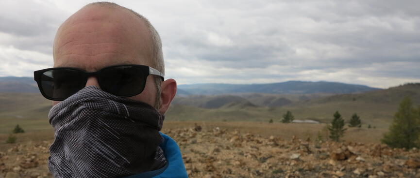 I pose in front of a rocky foreground and hilly background.