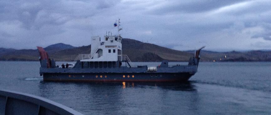 A flat blue ferry with a white cabin.
