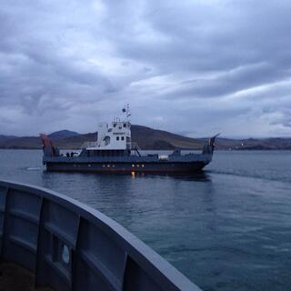 A flat blue ferry with a white cabin.