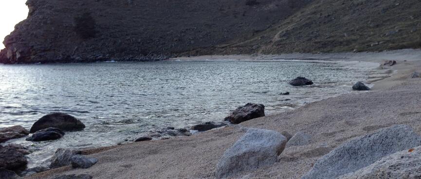 Coarse sand is punctuated by small rocks.